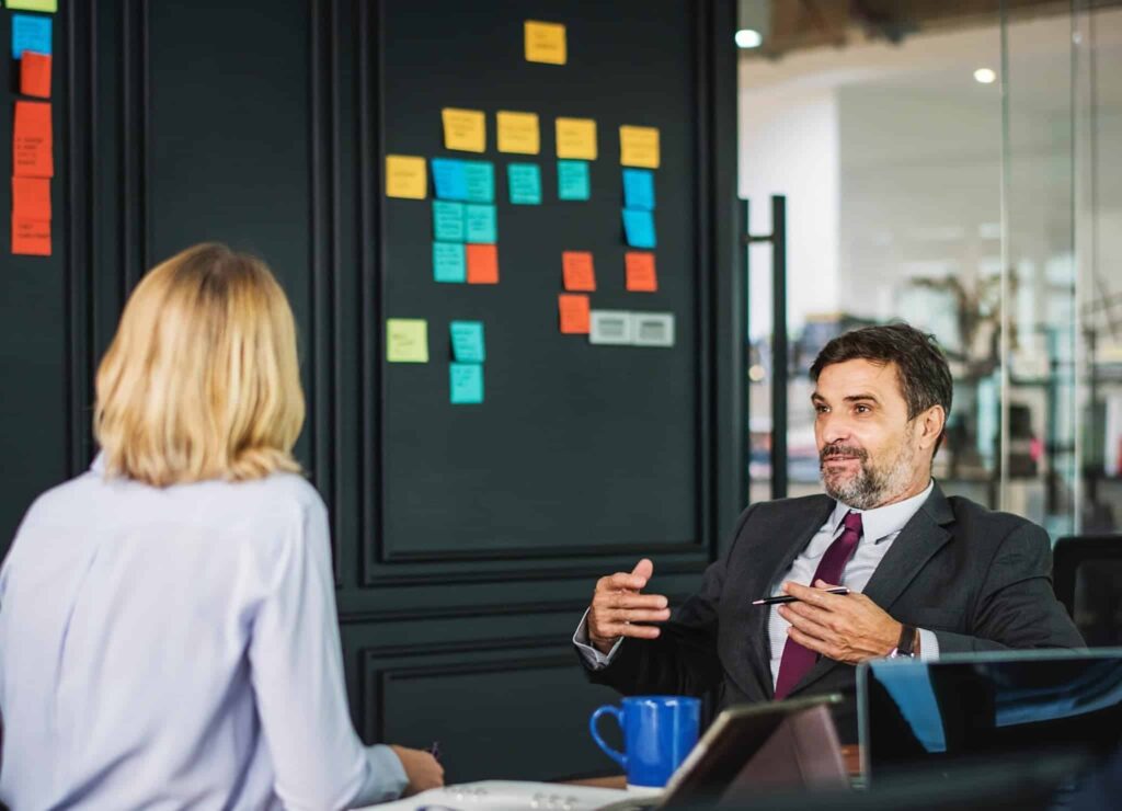 Two executives sitting at conference table discussing private equity portfolio management